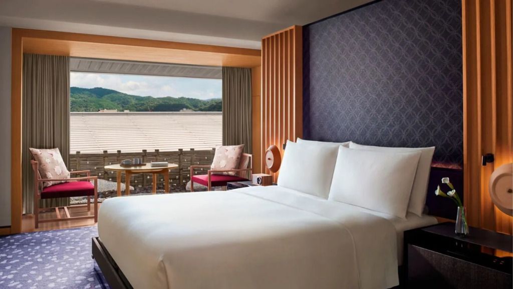 Komfortables Doppelbett in Suite mit Blick auf bewaldete Hügel