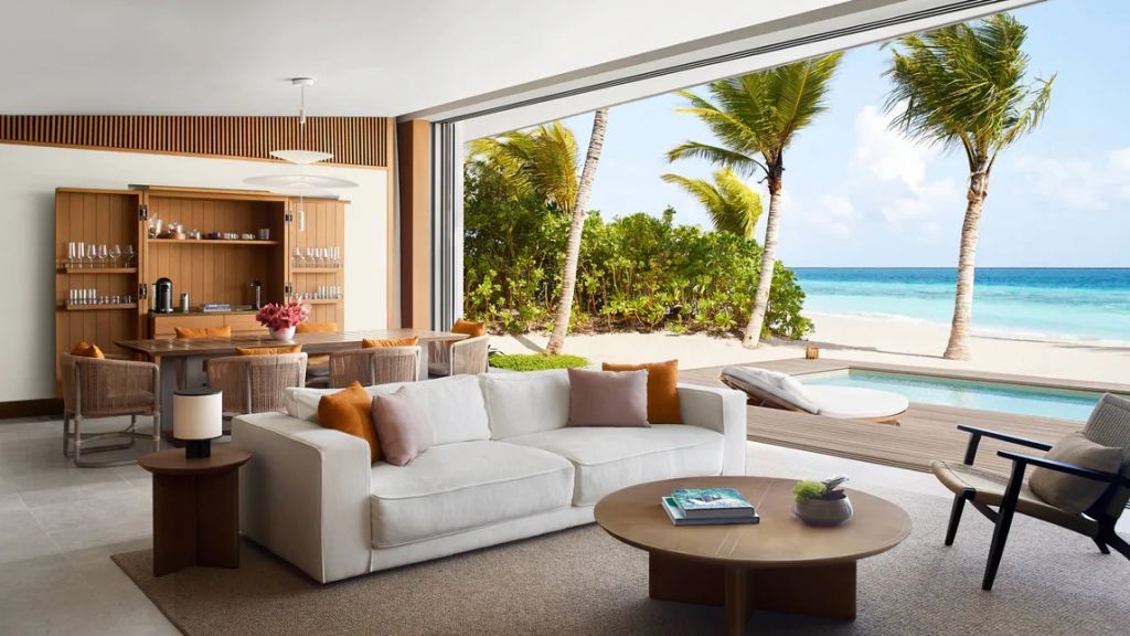 Helles Wohnzimmer der Beach Pool Villa mit Sofas, Esstisch und Blick auf Strand und Meer.