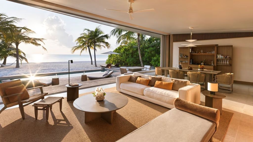 Luxuriöses Wohnzimmer mit offenem Blick auf den Strand und privatem Pool bei Sonnenuntergang.