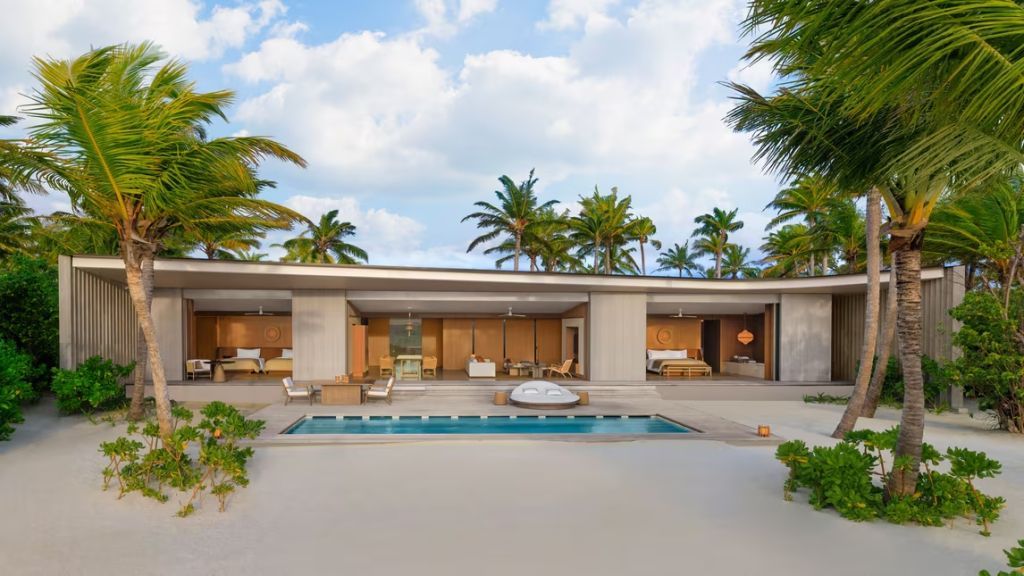 Lichtdurchflutete Beach Pool Villa mit Pool und Lounge-Bereich unter Palmen am Tag.