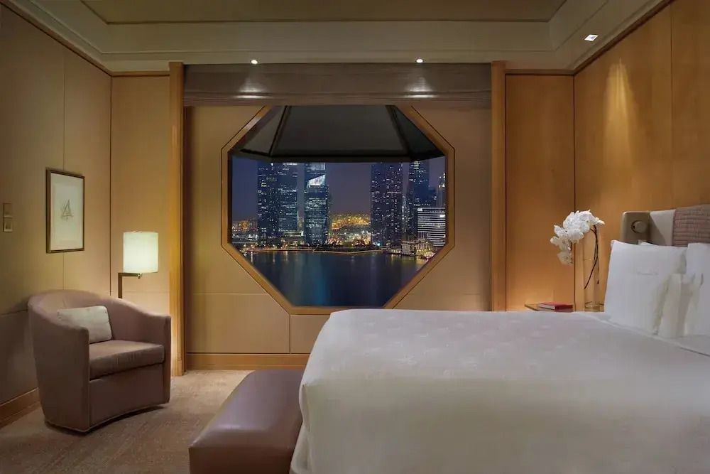 Luxuriöses Schlafzimmer mit atemberaubendem Blick auf Marina Bay bei Nacht.