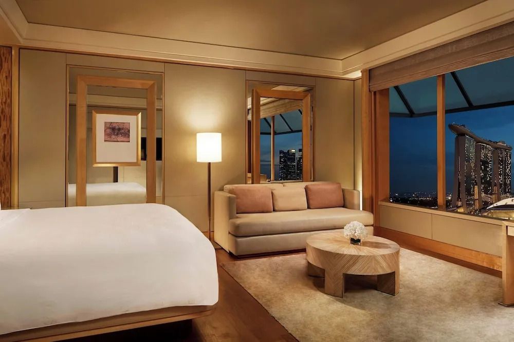 Deluxe-Zimmer im Ritz-Carlton mit stilvollem Sofa und nächtlichem Ausblick.