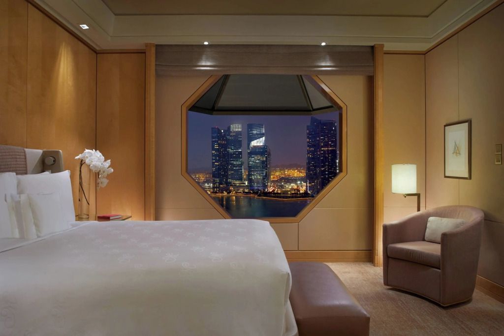 Luxuriöses Schlafzimmer mit Blick auf Marina Bay bei Nacht durch ein großes Fenster