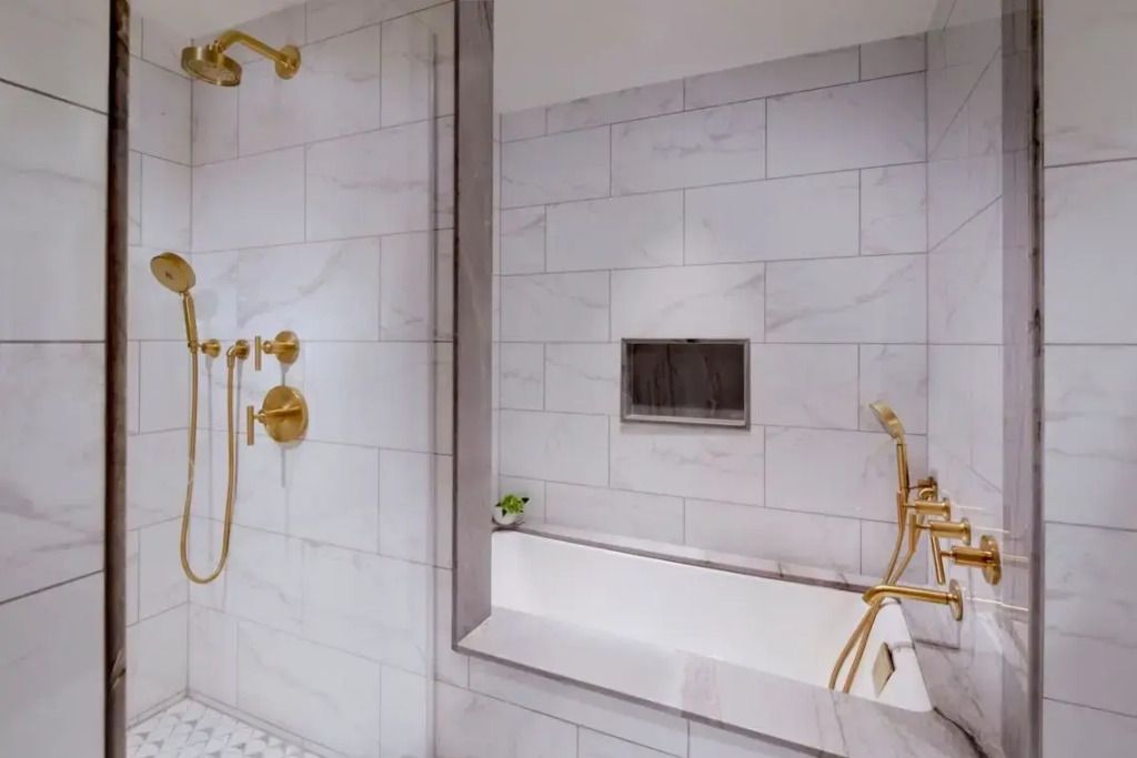 Badezimmer mit luxuriöser Marmordusche und goldenen Armaturen
