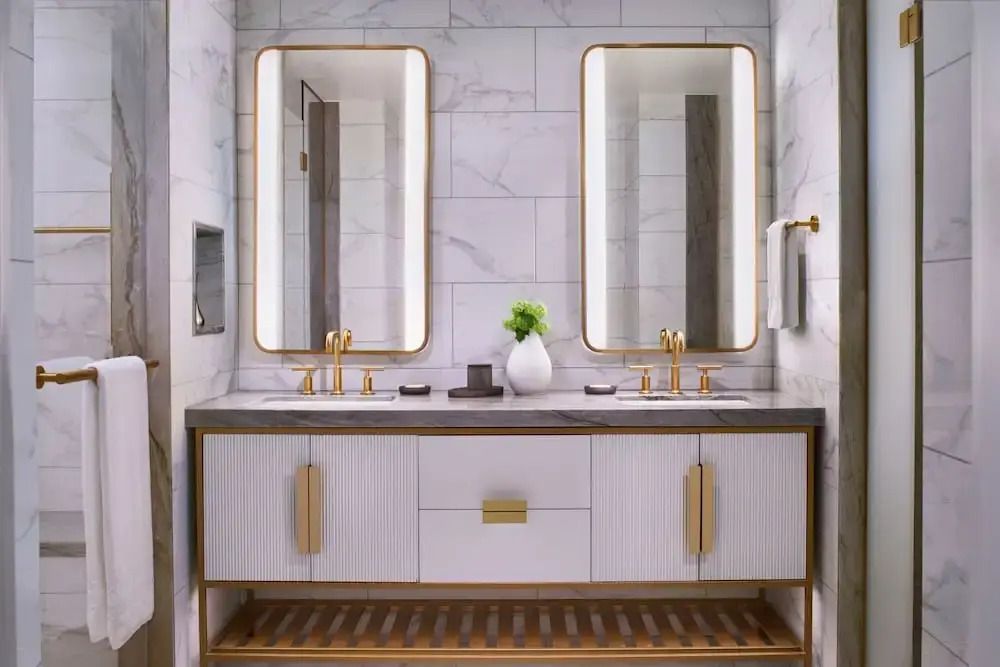 Marmorwaschtisch im Badezimmer mit zwei Spiegeln und goldenen Armaturen