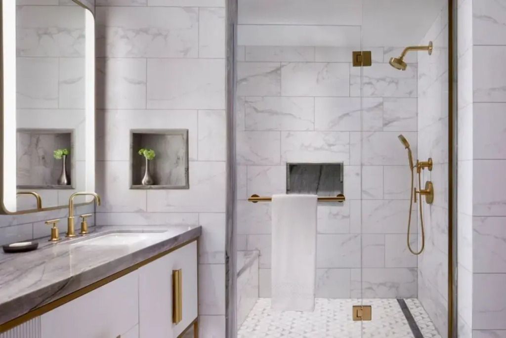 Luxuriöses Badezimmer mit Marmorfliesen und goldenen Armaturen.