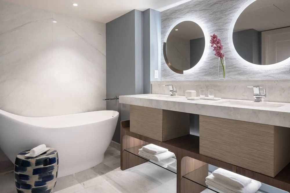 Modernes Badezimmer mit freistehender Badewanne und beleuchtetem Spiegel.