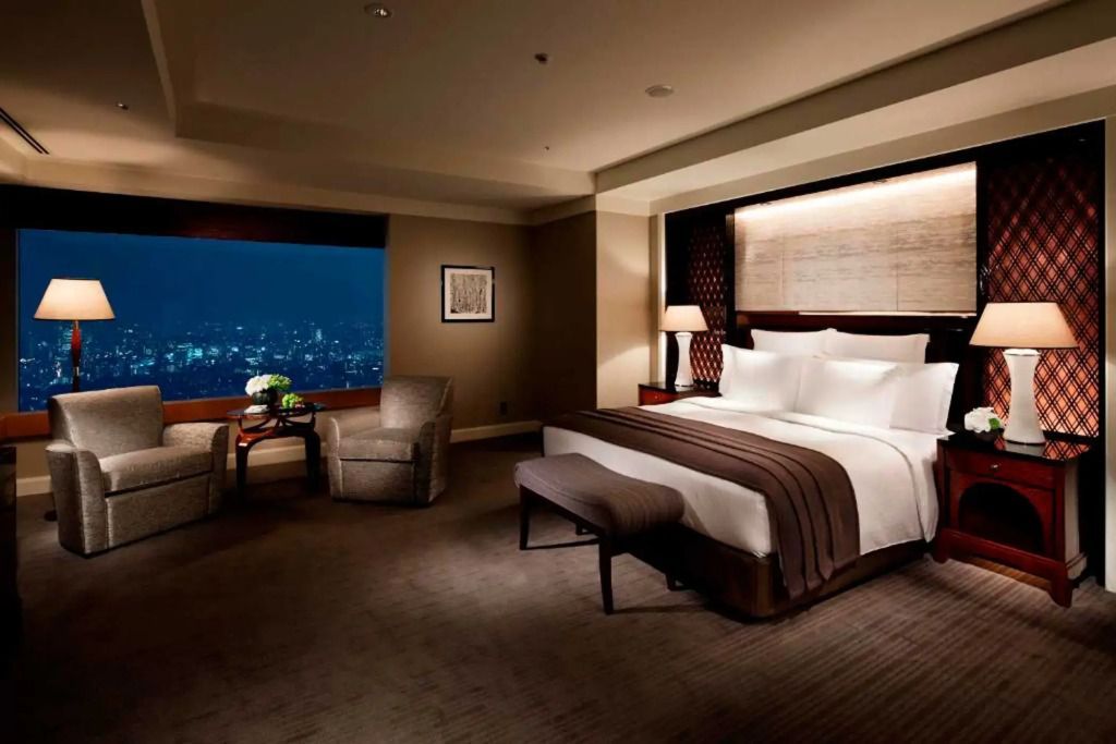 Elegantes Schlafzimmer mit nächtlichem Stadtblick in der Executive Suite.