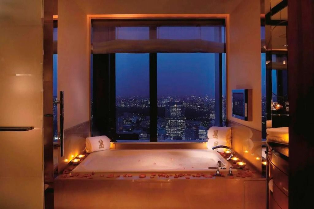 Stimmungsvolle Badewanne bei Nacht mit Kerzenschein und Stadtblick