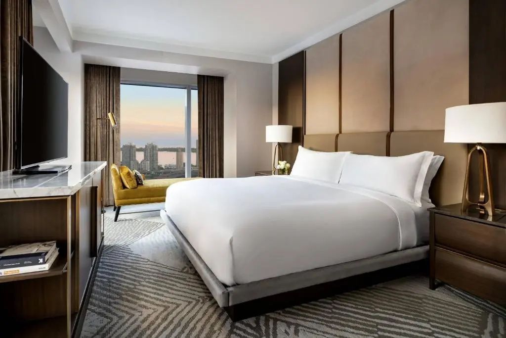 Luxuriöses Schlafzimmer mit weichem Teppich und großem Doppelbett in Suite mit Stadtblick