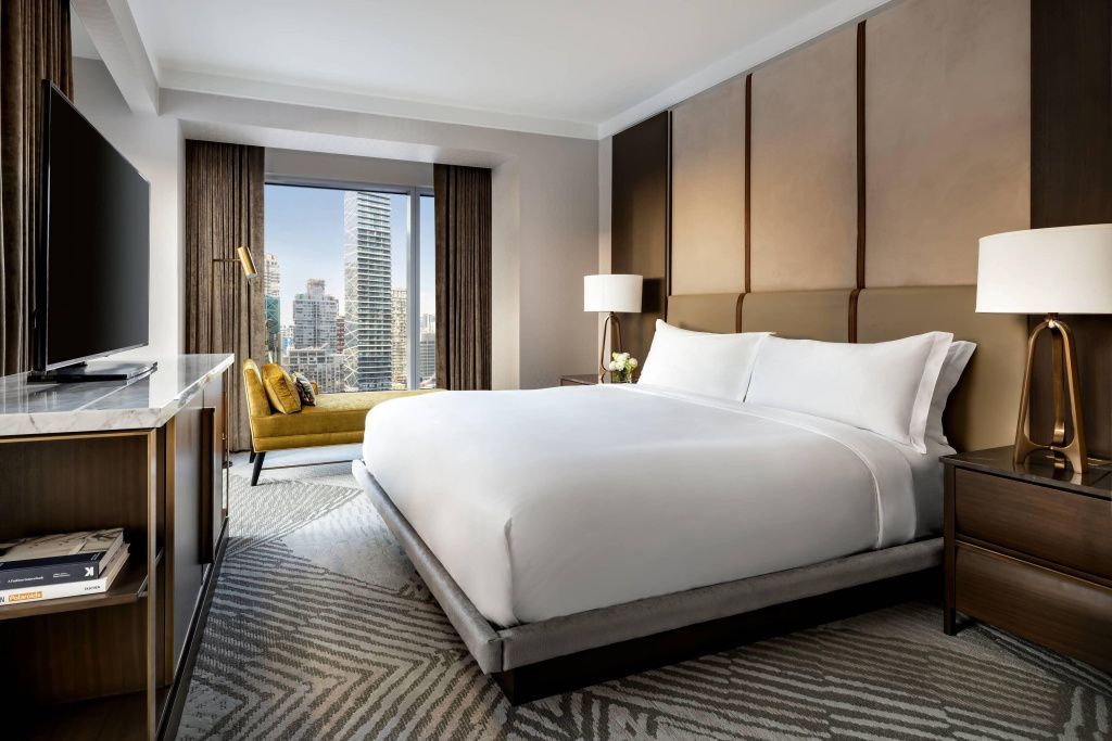 Ecke Suite mit modernem Doppelbett und Stadtblick durch großes Fenster