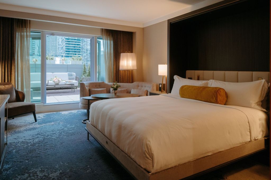 Elegantes Hotelzimmer mit Doppelbett und Zugang zur Terrasse mit Stadtblick