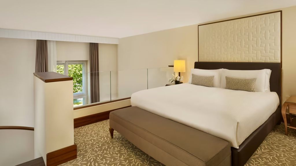Elegantes Schlafzimmer einer Duplex Suite mit großem Bett und Blick auf den Garten