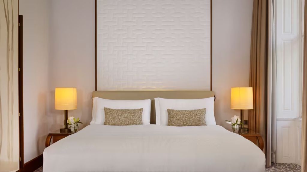 Luxuriöses Bett in der Junior-Suite mit eleganten Lampen und dekorativen Kissen