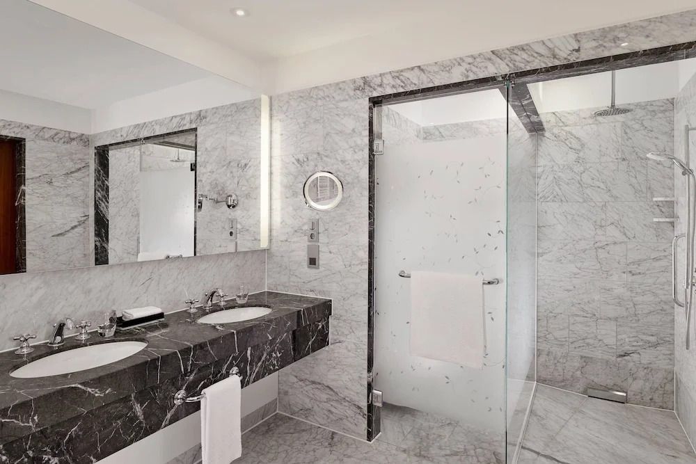 Modernes, helles Badezimmer mit Glasdusche und stilvollen Marmordetails