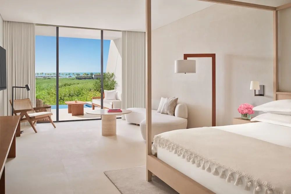 Geräumiges Hotelzimmer mit Doppelbett, modernem Dekor und Balkon mit Meerblick.
