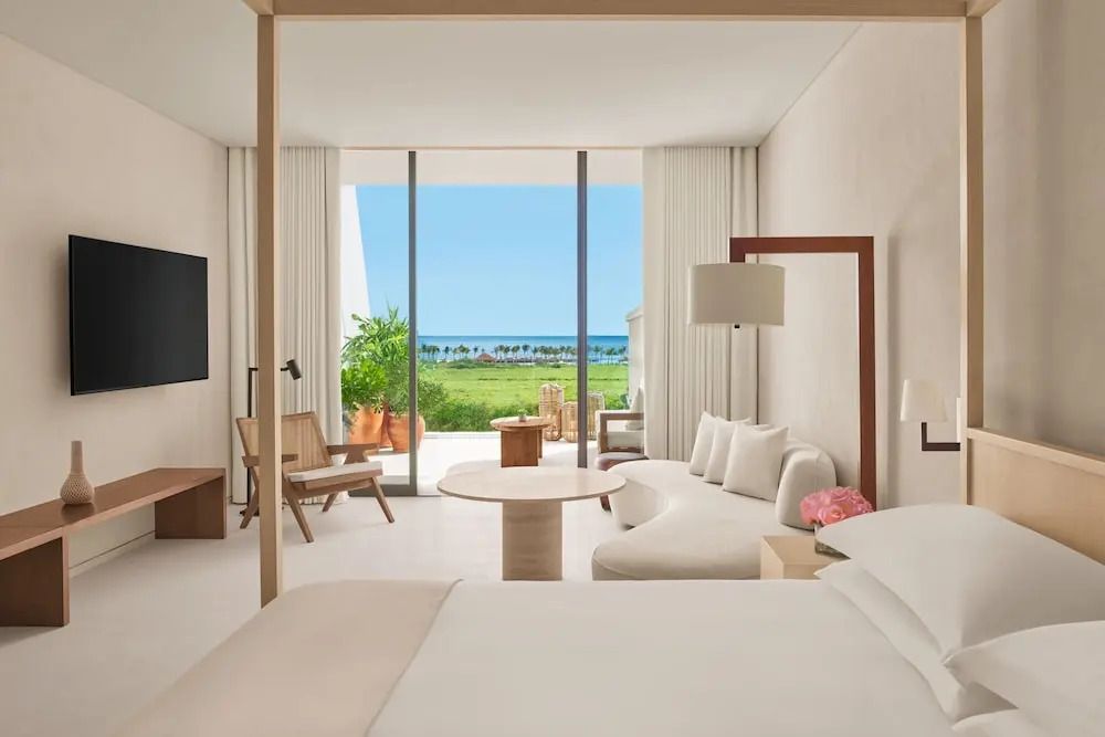 Modernes Zimmer mit Doppelbett, Sitzecke und Meerblick vom Balkon.