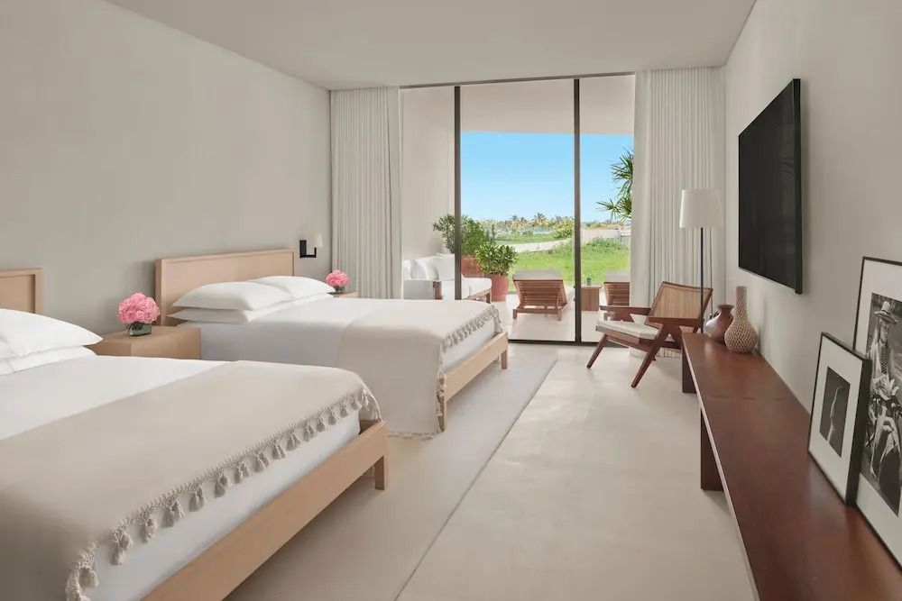 Helles Schlafzimmer mit zwei Betten und Balkon mit Meerblick