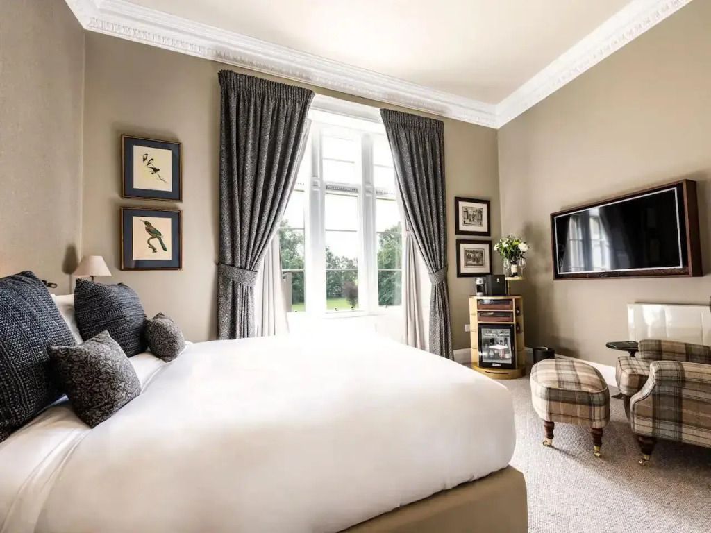 Geräumiges Zimmer mit Kingsize-Bett und großem Fenster mit Vorhängen.