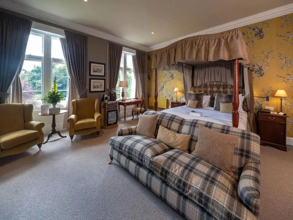 Helle Junior-Suite mit großem Sofa und Himmelbett in historischem Stil