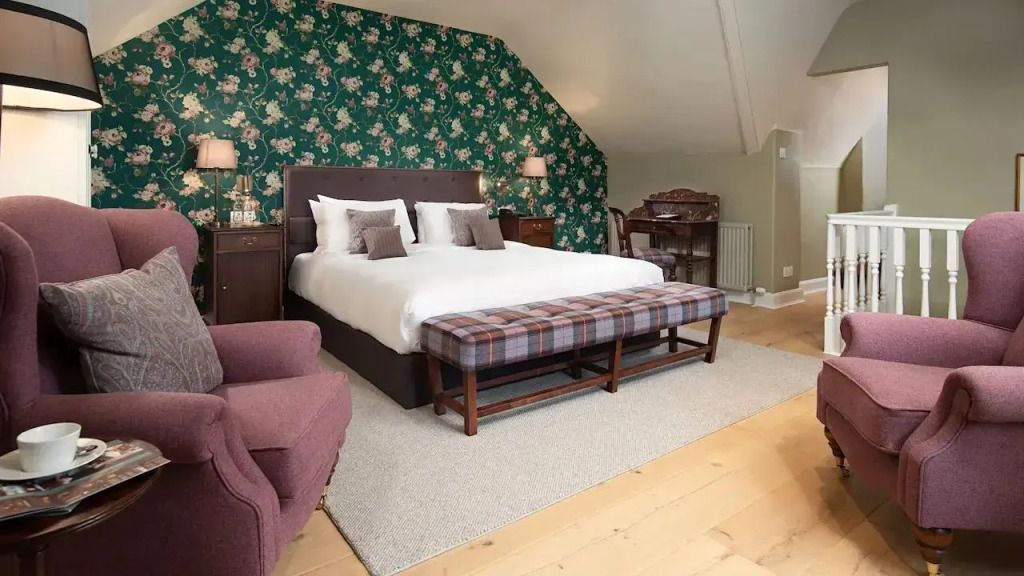 Elegantes Doppelbett mit gemusterter Tapete und gemütlichem Sessel