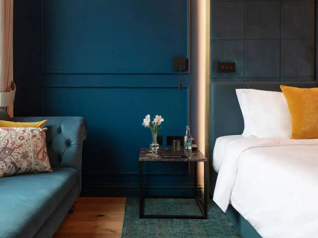 Beistelltisch mit Blumen neben Couch im stilvollen Schlafzimmer