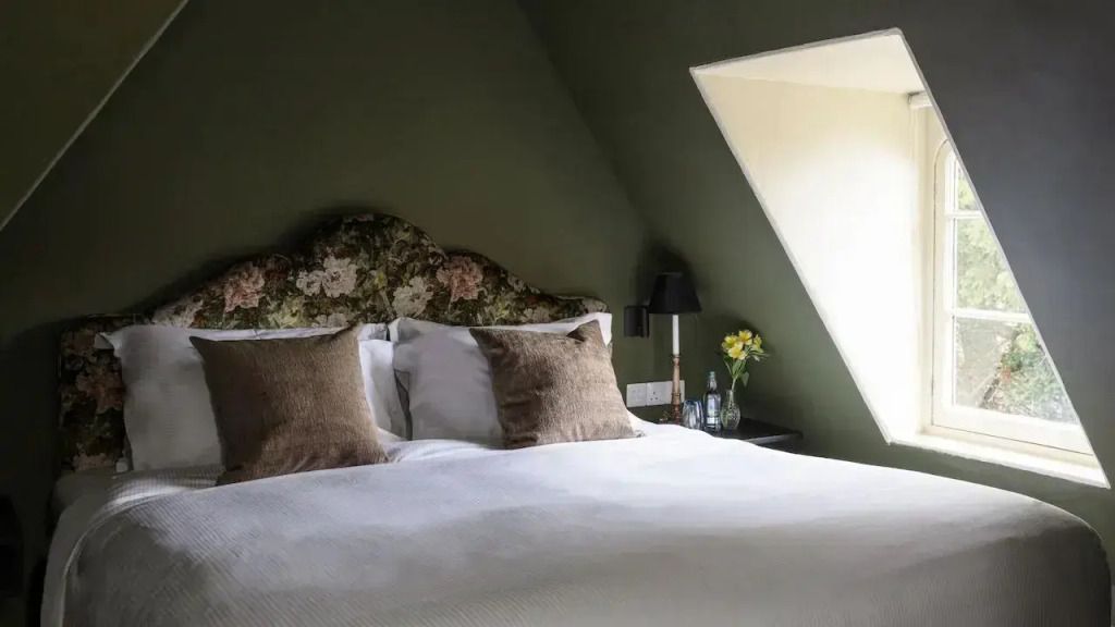 Elegantes Schlafzimmer mit grünem Akzentwand und Blumenmuster-Kopfteil.