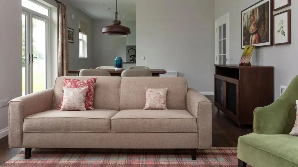 Wohnbereich mit beigem Sofa und stilvollen Kissen vor Essbereich