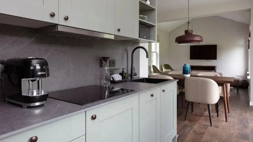 Moderne Küche mit hellen Schränken und Esstisch im Hintergrund