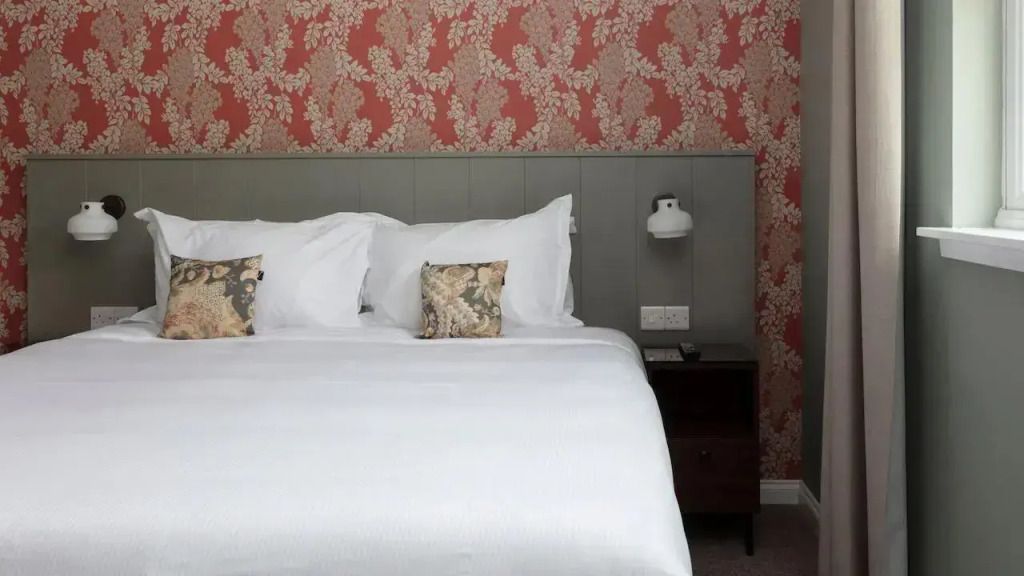 Gemütliches Schlafzimmer mit attraktivem, floralem Tapetendesign und eleganten Kopfkissen.