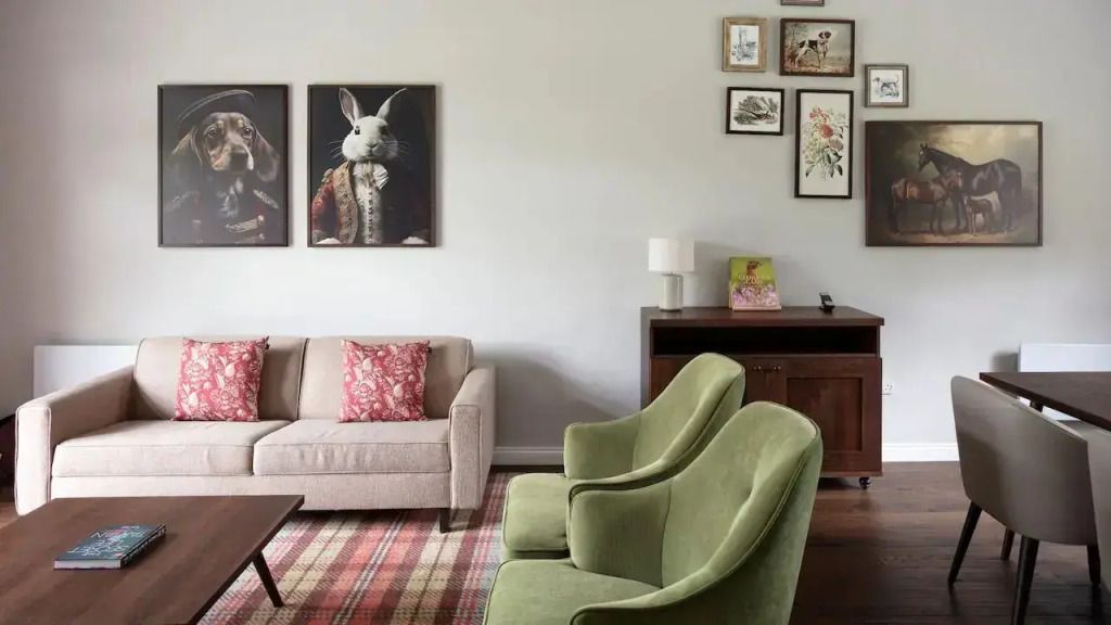 Elegantes Wohnzimmer mit gemütlichen Sofas, grünen Sesseln und dekorativen Wandbildern.