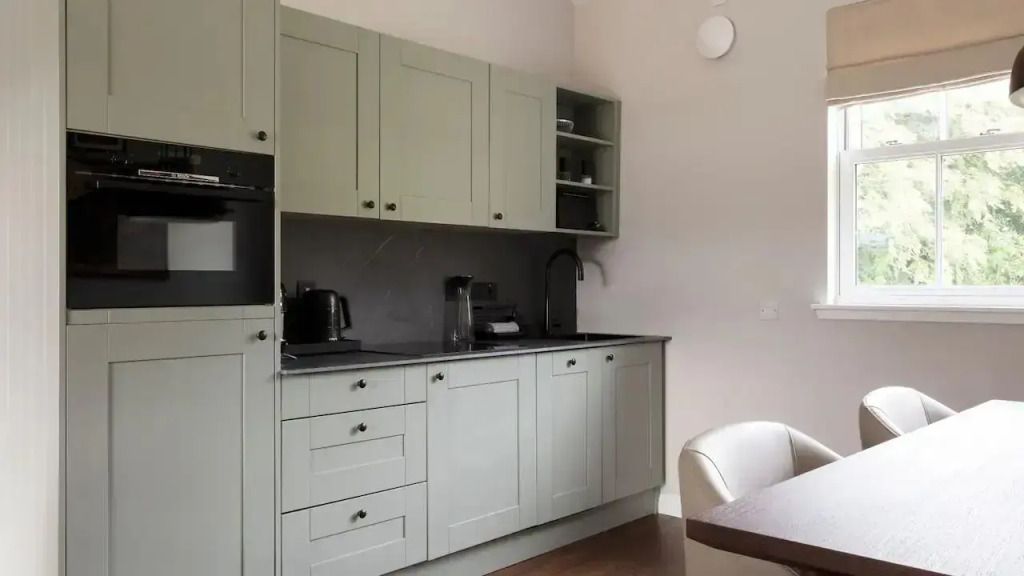 Moderne Küche mit grauen Schränken und eleganten Geräten in minimalistischer Ausführung.