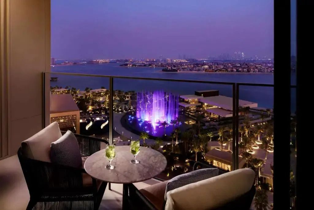 Balkon mit Blick auf das abendliche Dubai und beleuchtete Wasserspiele