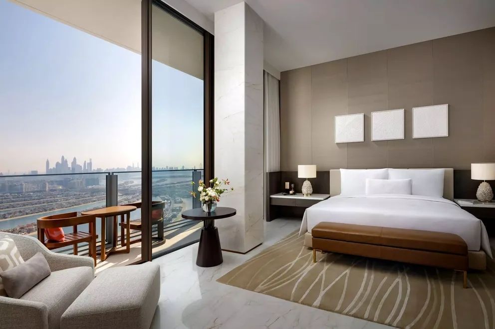 Helles Schlafzimmer mit großem Fenster und Balkonblick auf die Skyline.