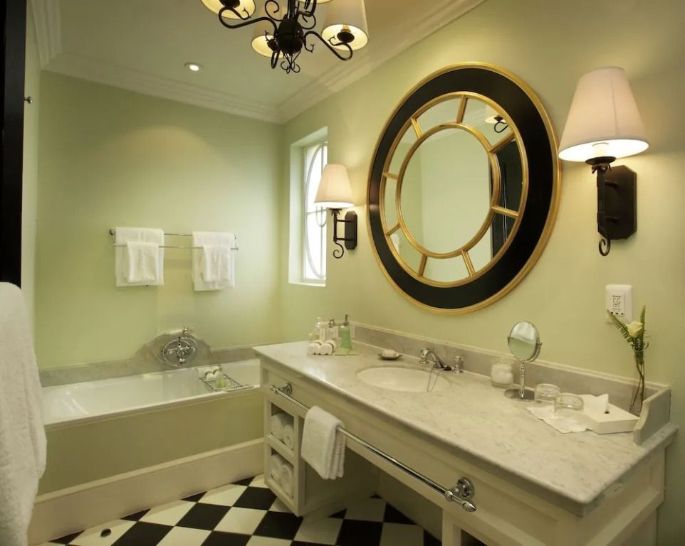 Elegantes Badezimmer mit großem Spiegel und grünen Wänden im Hotelzimmer