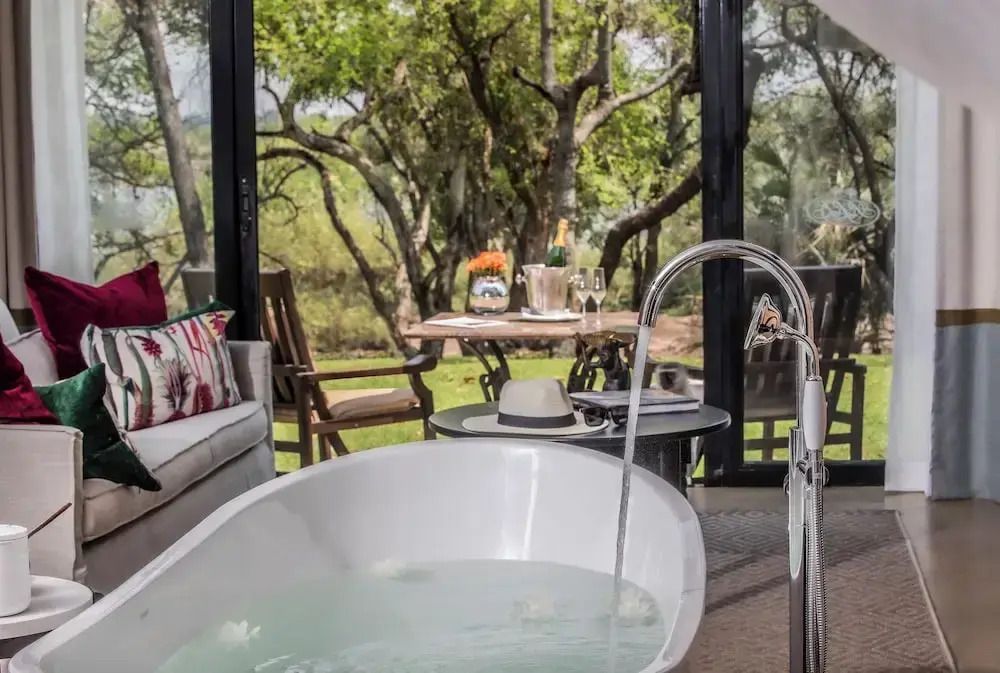 Suite mit freistehender Badewanne und Blick auf die Terrasse mit Waldlandschaft