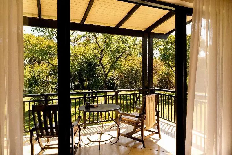 Balkon mit zwei Holzstühlen und Blick auf einen grünen Garten