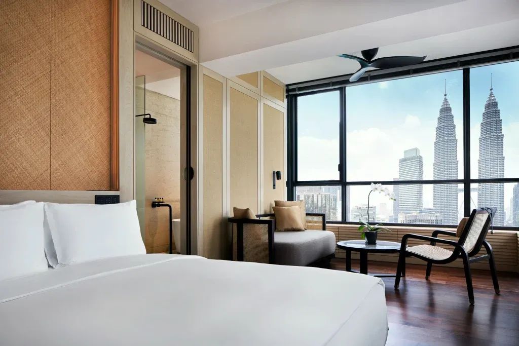 Modernes Hotelzimmer mit Blick auf ikonische Zwillingstürme durch großes Fenster.