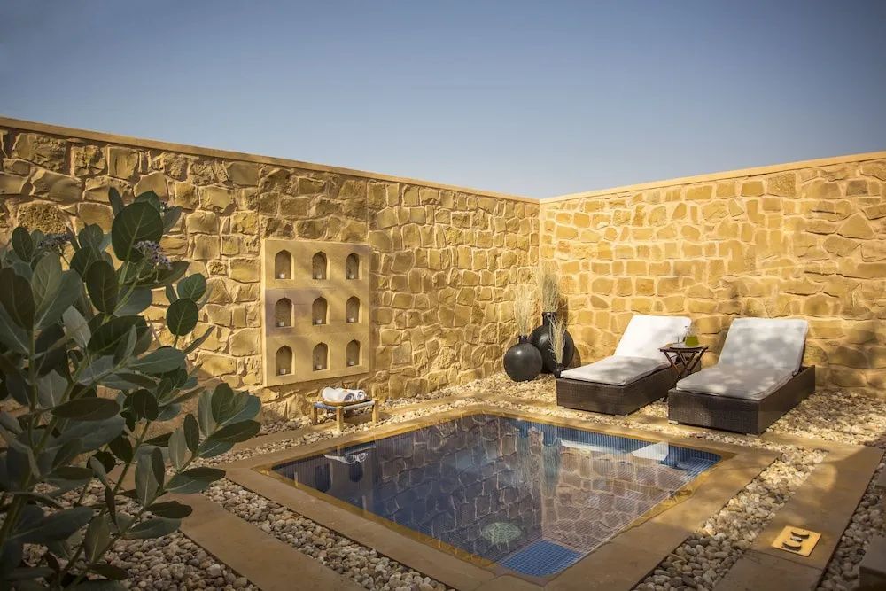Privater kleiner Pool mit bequemen Liegestühlen und Steinmauer