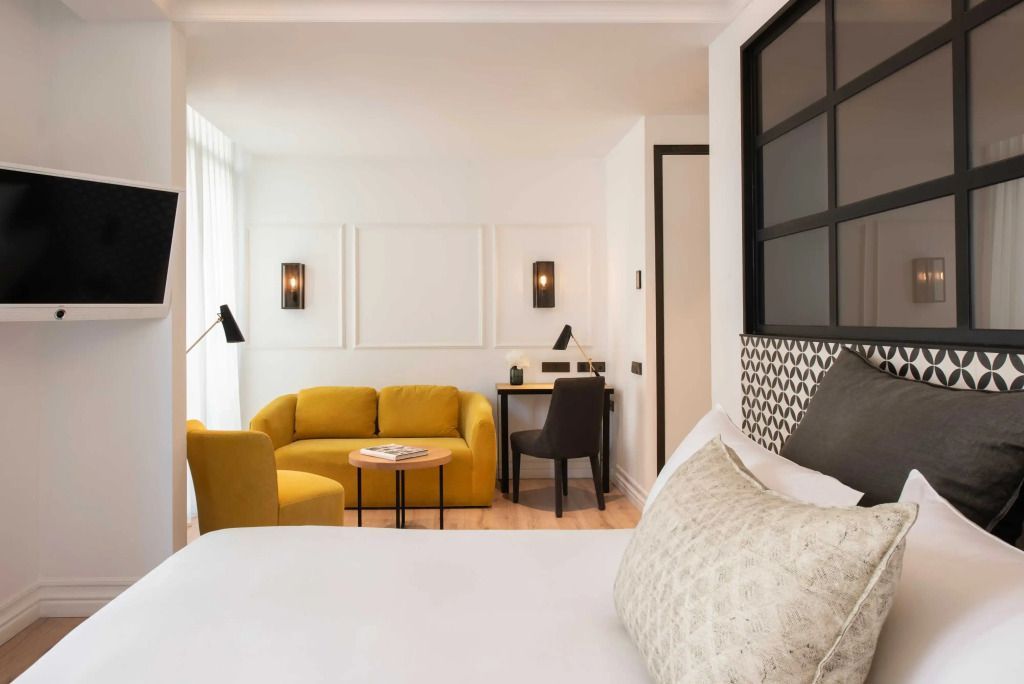 Helles Deluxe Doppelzimmer mit weißem Interieur und gelber Sitzecke