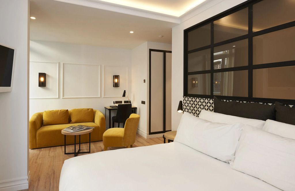 Modernes Hotelzimmer mit Doppelbett und gelber Sitzecke