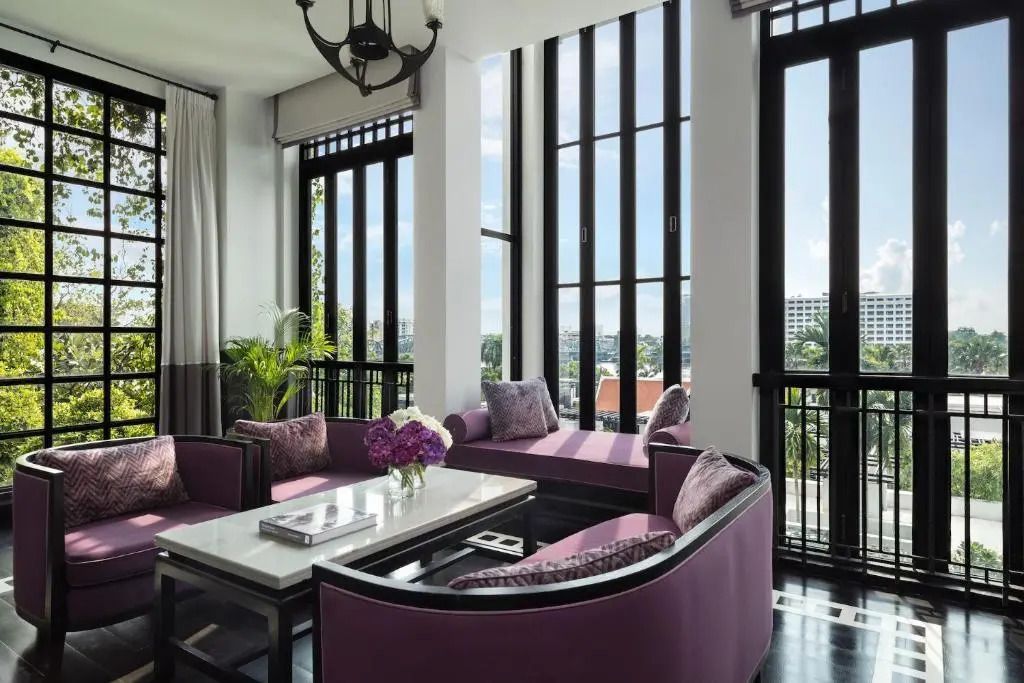 Elegantes Wohnzimmer der Premier Suite mit großen Fenstern und violetten Sofas