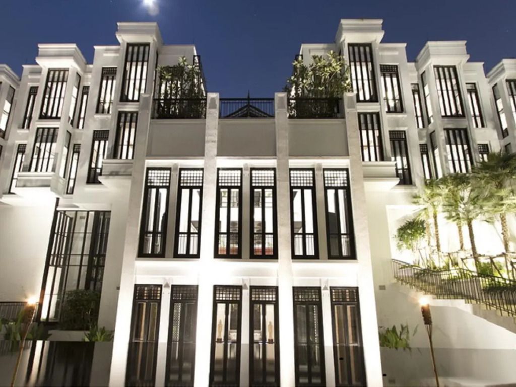 Historische Fassade des Hotels The Siam bei Nacht mit beleuchteten Fenstern.