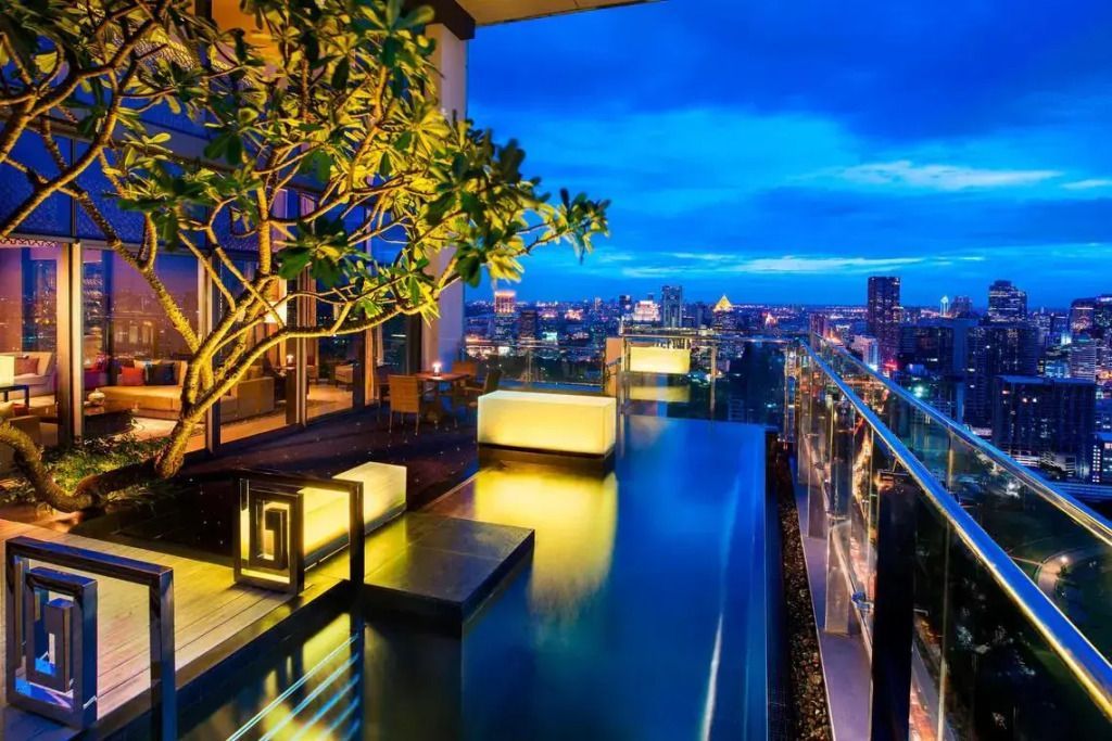 Infinity-Pool auf der Terrasse mit Blick auf die erleuchtete Skyline von Bangkok