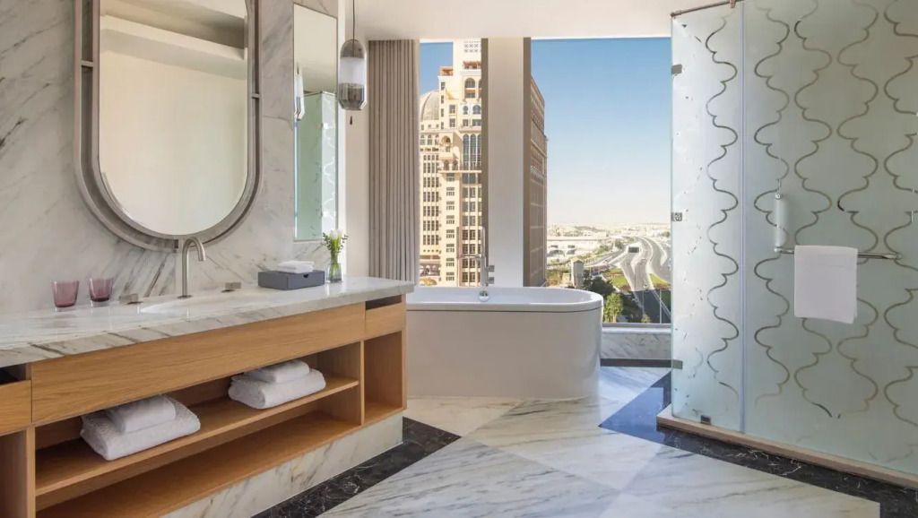 Luxuriöses Badezimmer mit freistehender Badewanne und direktem Blick auf die Skyline von Doha.