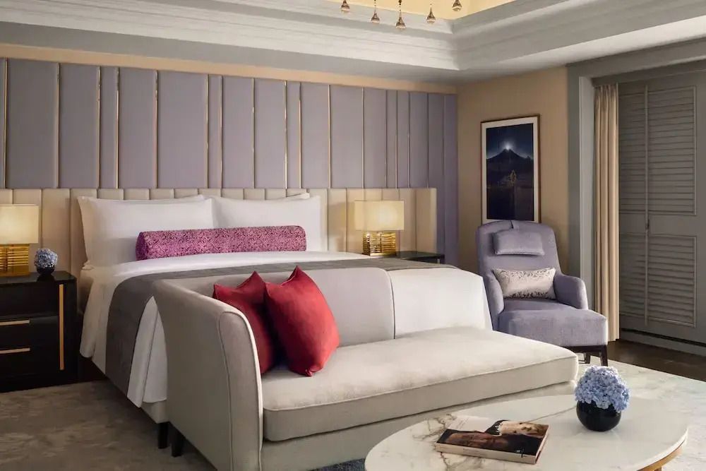 Luxuriöses Schlafzimmer in der Suite mit gemütlichem Sofa und großen Fenstern in Jakarta