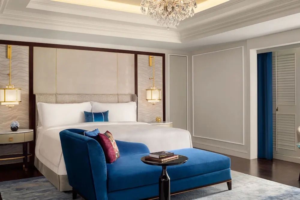 Elegantes Schlafzimmer mit luxuriösem Bett und blauer Chaiselongue in Jakarta