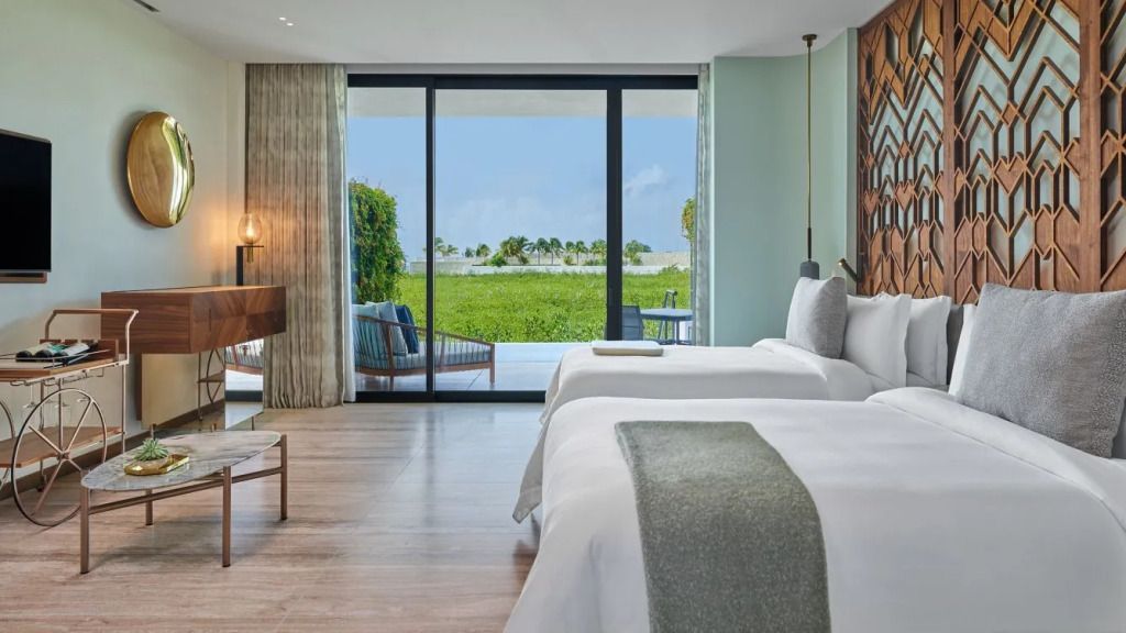 Geräumiges Hotelzimmer mit zwei Betten, Sitzbereich und Zugang zu einer Terrasse mit Aussicht.