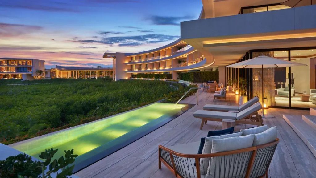 Abendlicher Blick auf die moderne Architektur des Resorts mit beleuchtetem Infinity Pool.