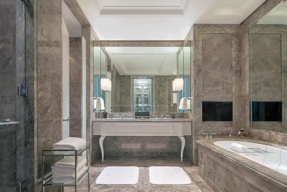 Luxuriöses Badezimmer mit Marmorverkleidung und freistehender Badewanne